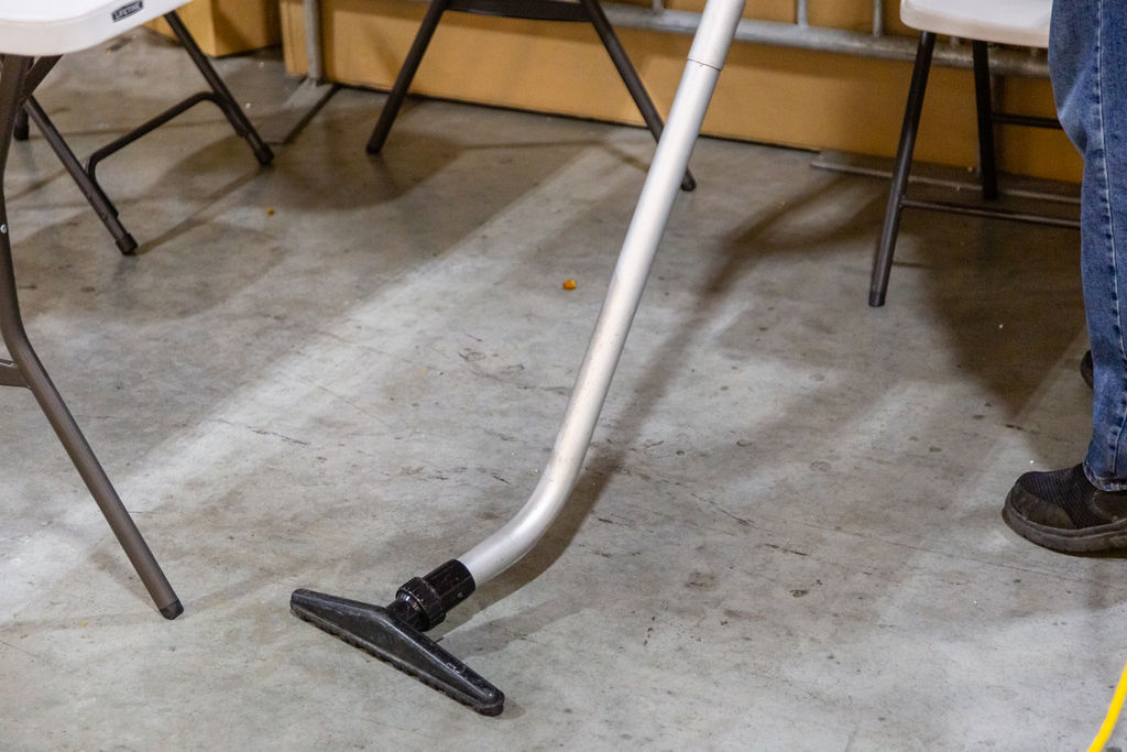 Man cleaning the floor with vacuum cleaner in warehouse