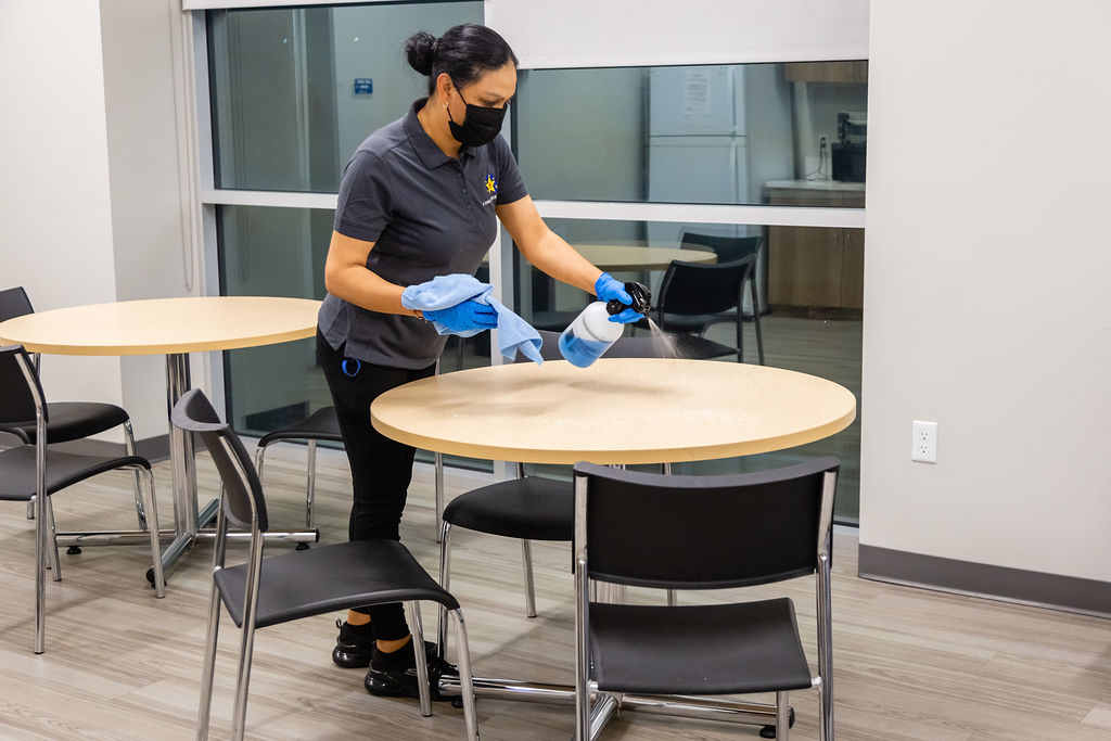 Woman sanitizing the table with cleaning spray